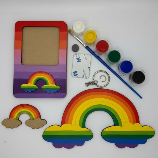 Craft materials including a rainbow-themed picture frame, paint, brush, and rainbow decorations on a white background.