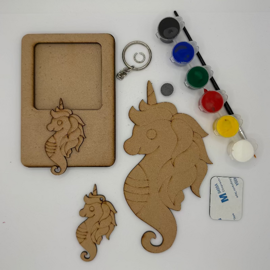Unicorn and seahorse-shaped wooden cutouts with paint containers and a brush on a white background
