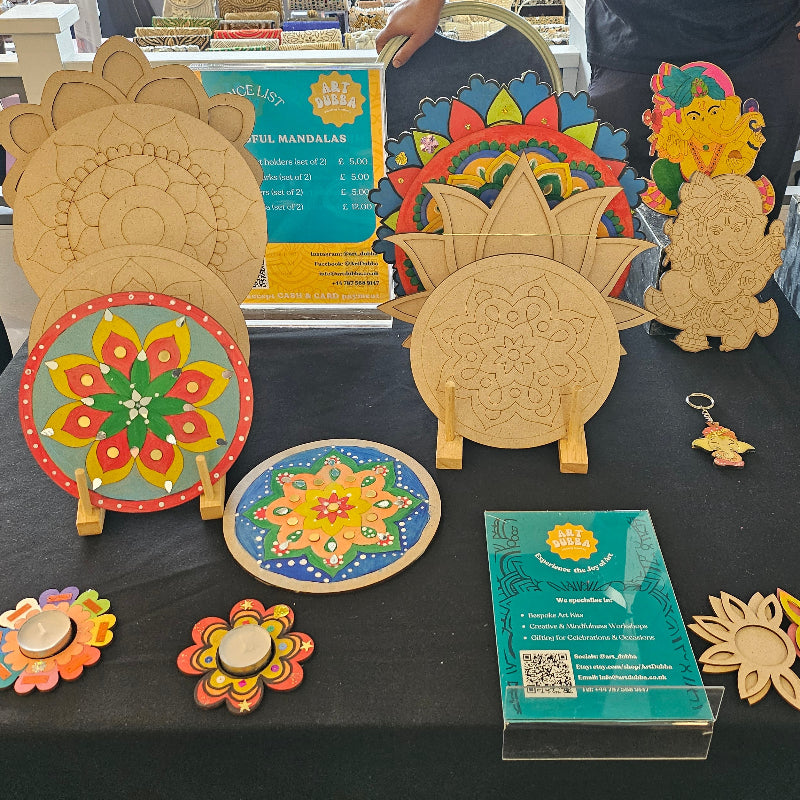 Colourful wooden Mandala crafts on display at an event with people in the background.