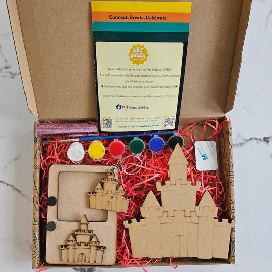 Craft kit with wooden castle pieces, paint bottles, and instructions on a marble surface.