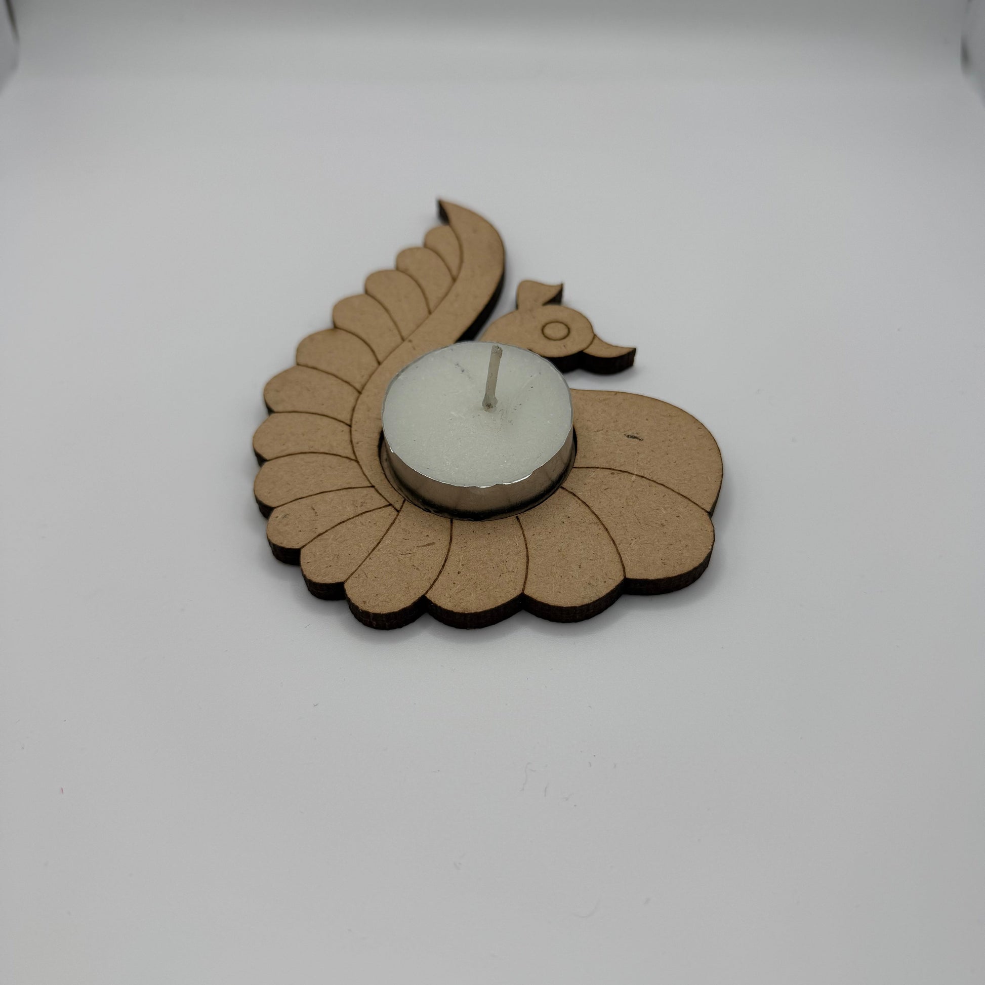 Decorative tealight holder peacock design on a plain white wall