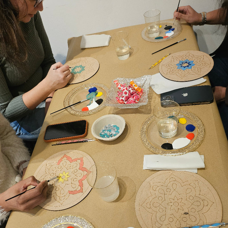 Corporate People painting mandalas on mandala bases at a table with art supplies.