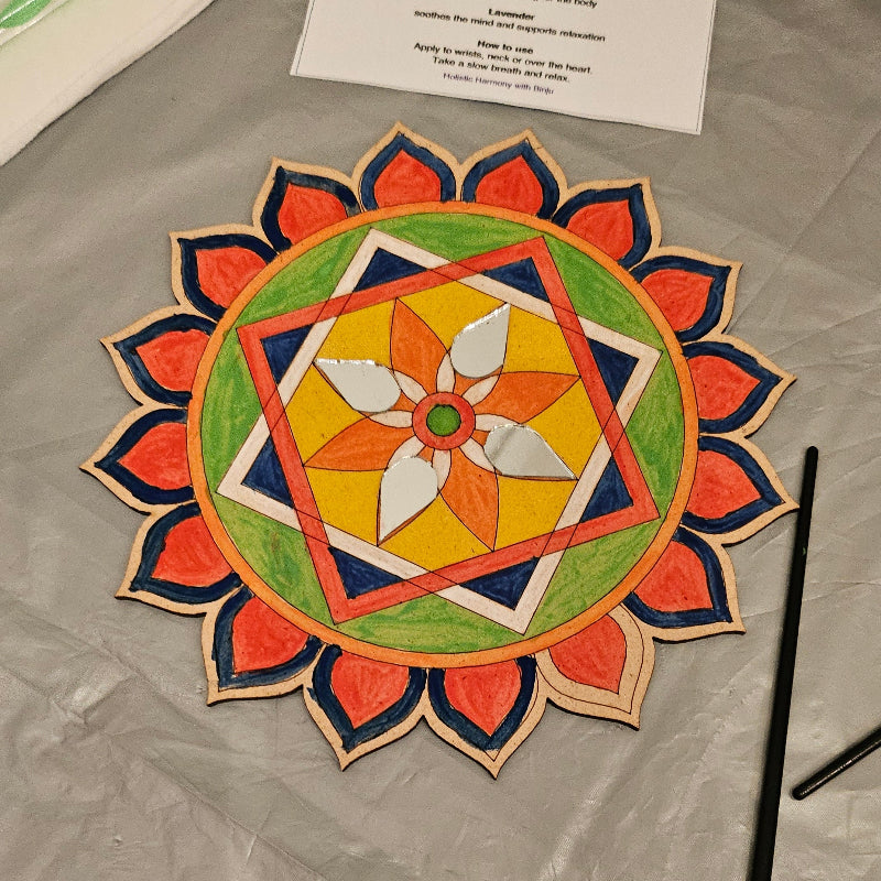 Colorful mandala design on a textured surface with art supplies.