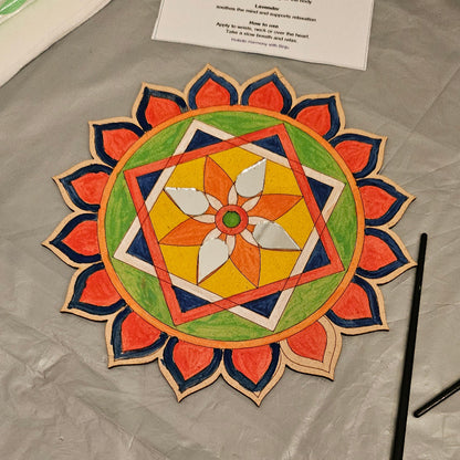 Colorful mandala design on a textured surface with art supplies.