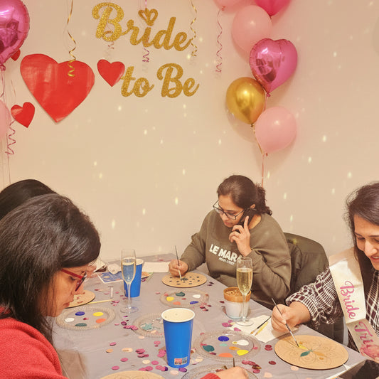 Group of people engaged in a painting activity at a table with art supplies.