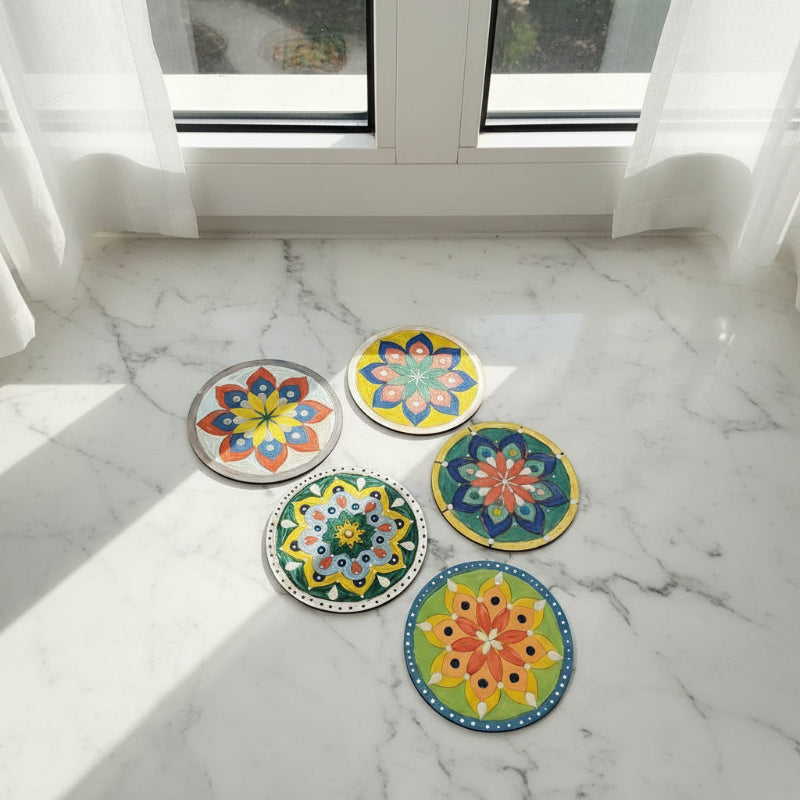 Five colourful mandala designs on a marble surface.