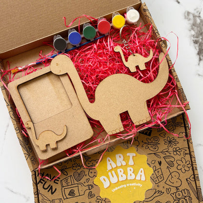 Dinosaur box with art supplies including wooden elephant shapes and markers, branded 'Art Dubba'.