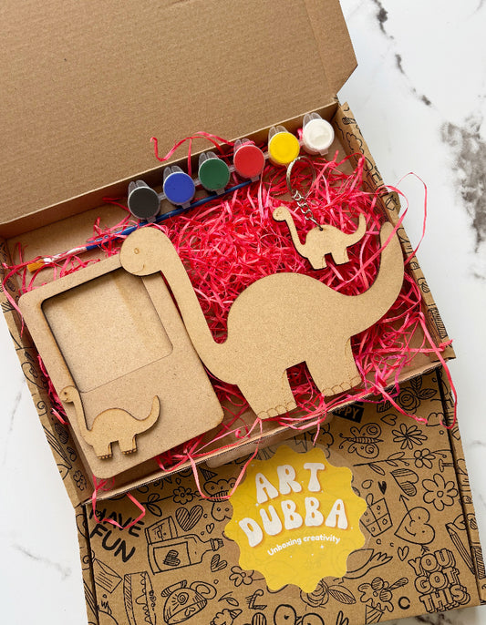 Cardboard box with art supplies including wooden elephant shapes and markers, branded 'Art Dubba'.
