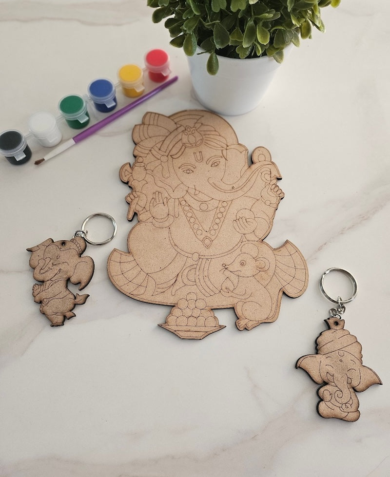 Wooden Ganesha cutout with keychains and paint supplies on a light surface.