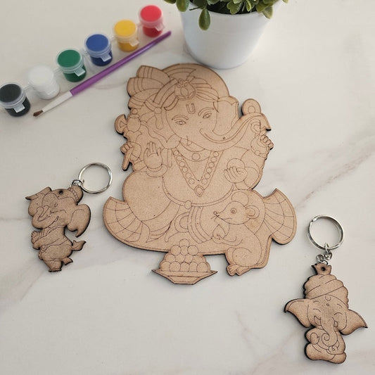 Wooden Ganesha cutout with keychains and paint supplies on a light surface.