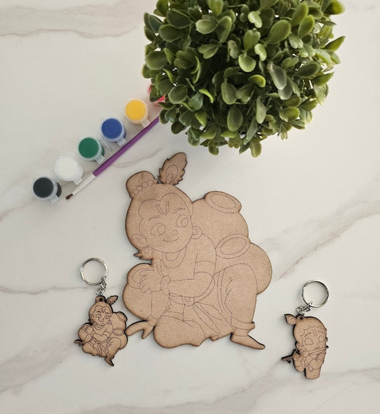 Wooden cutout of Krishna with two keychains on a light surface with a green plant.