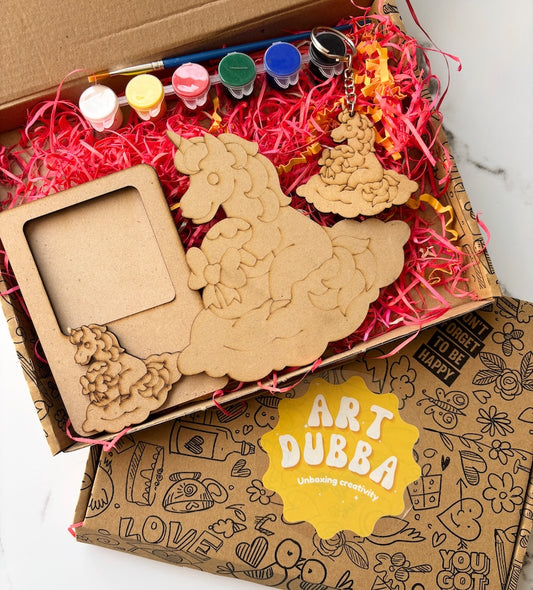 Unfinished wooden unicorn craft kit with paint bottles and a brush in a box labeled 'Art Dubba'.