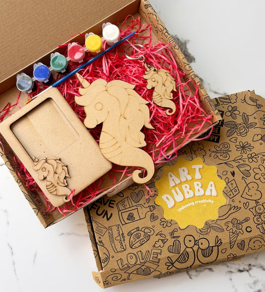 Wooden unicorn and seahorse ornaments in a 'Art Dubba' box with paint supplies.